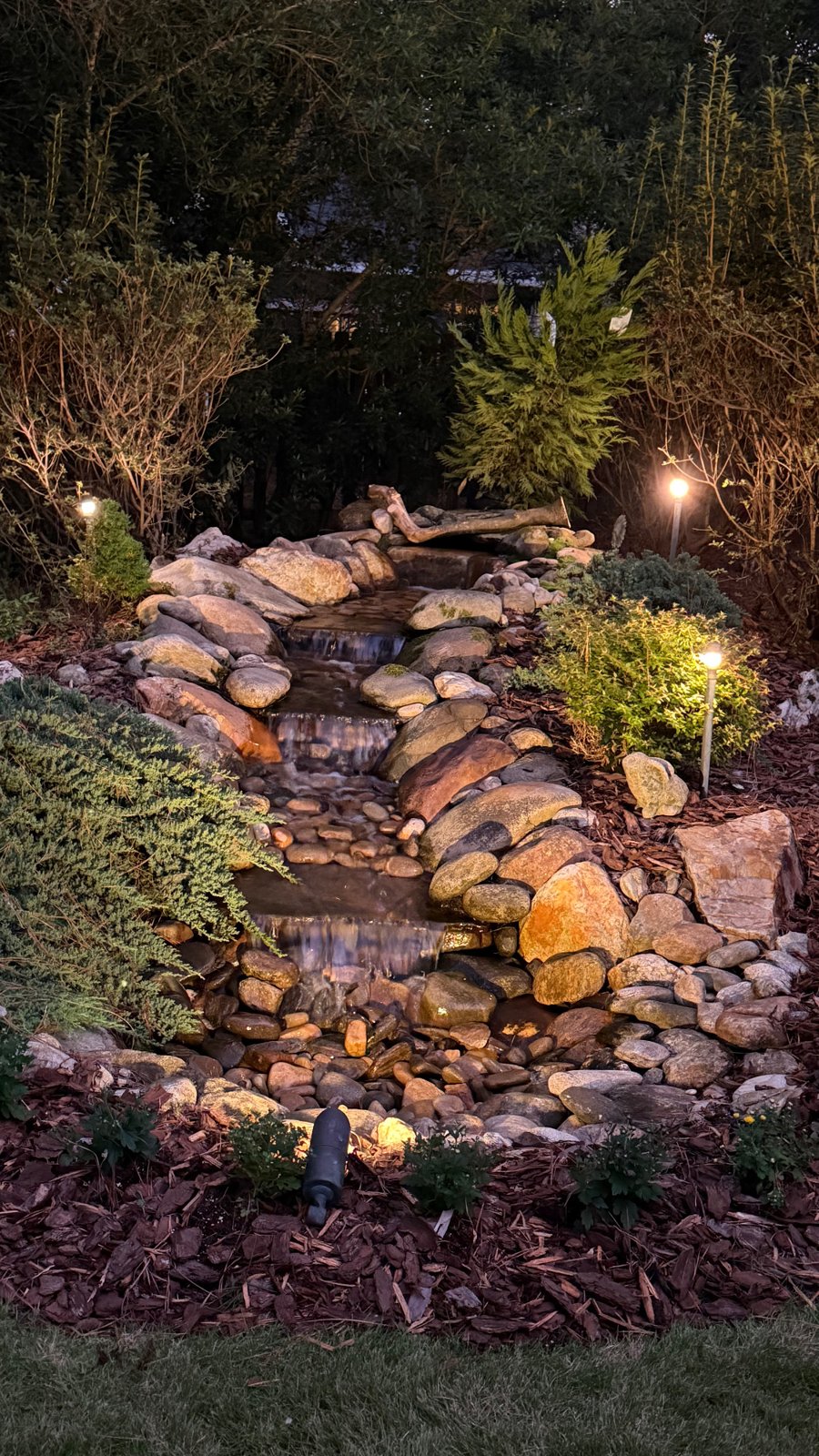 The same rock waterfall by day and lit at night